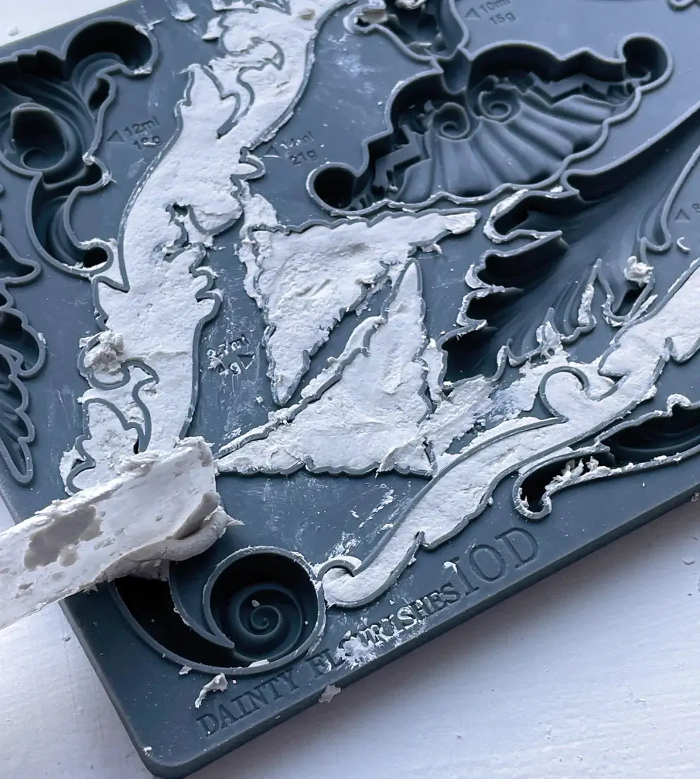 IOD Dainty Flourishes Decor Mould showing intricate scrollwork design in grey silicone with a white clay sample.