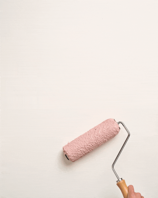 Why Choose Annie Sloan Wall Paint: applying soft pink paint with a roller on a white wall.