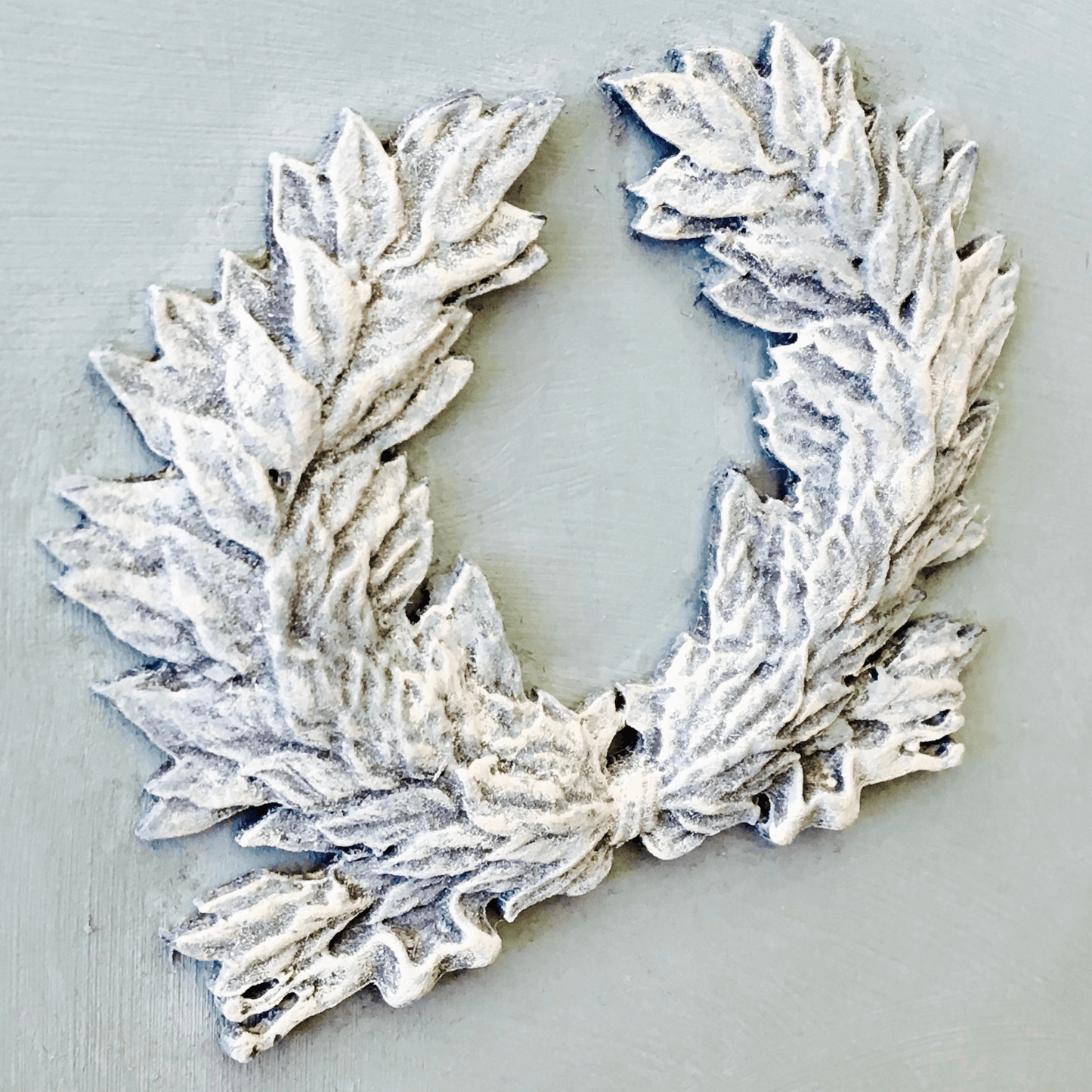 Decorative laurel wreath furniture applique painted and waxed on light grey background