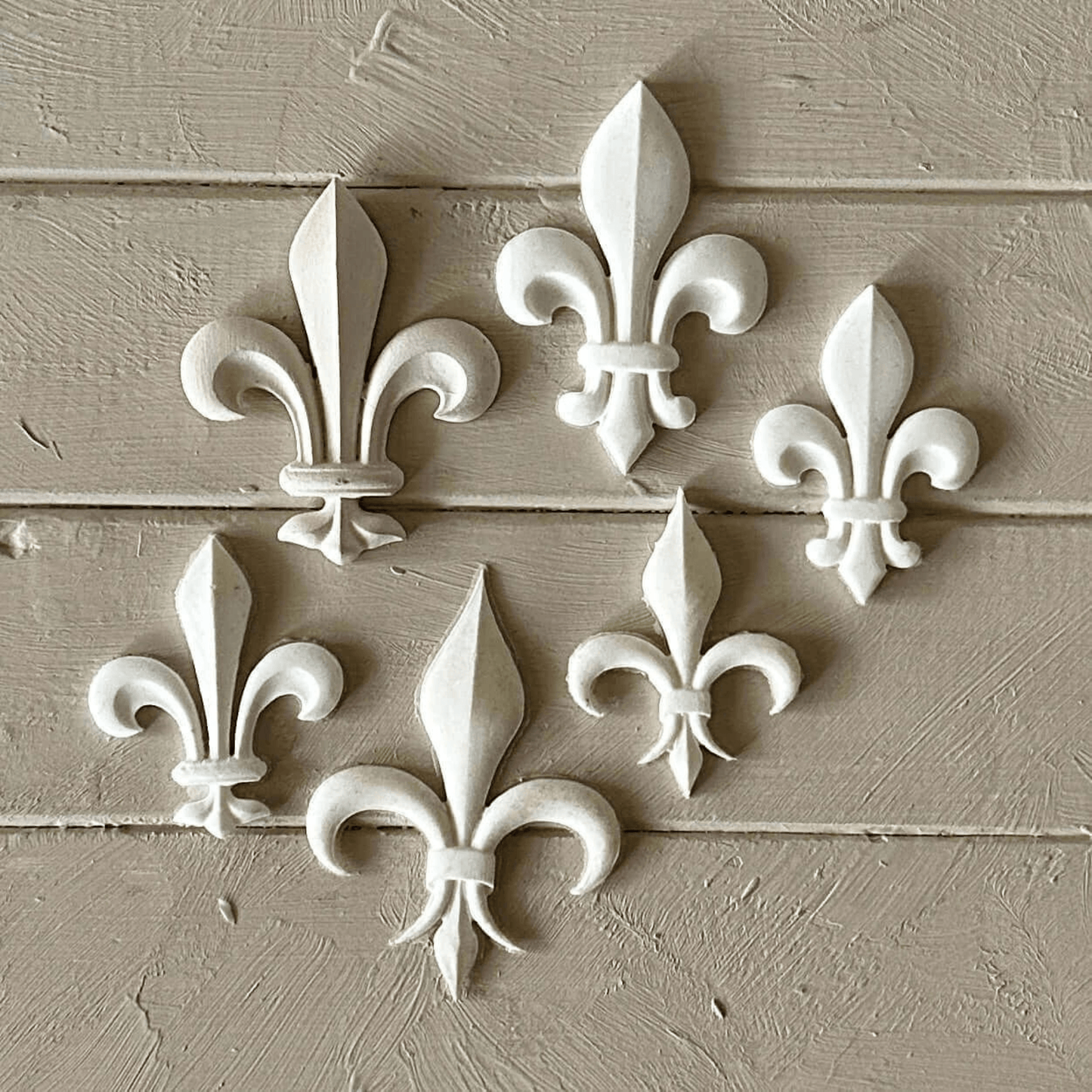 Fleur De Lis 002 - Resin Applique for Furniture & Crafts displayed in six elegant white designs on a wooden surface.