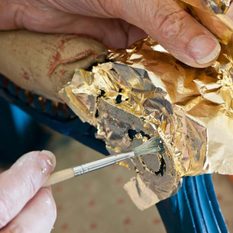 Annie Sloan Gold Size being brushed onto gold leaf for gilding on a curved surface.