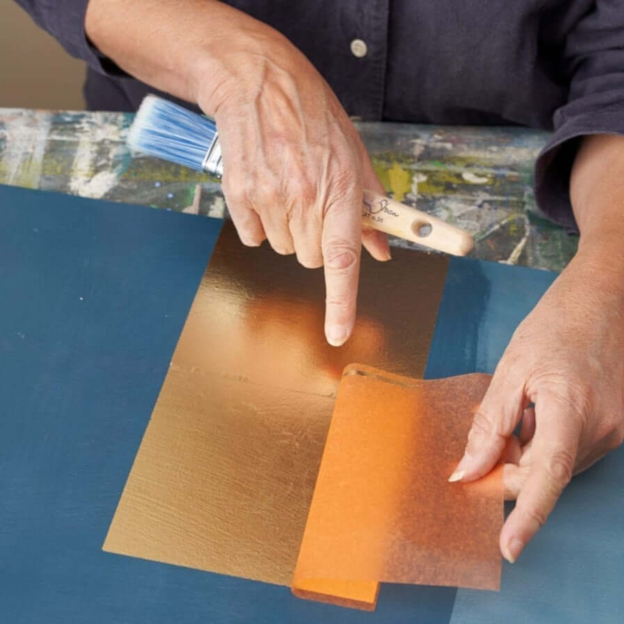 Hands apply Annie Sloan Gold Size, a water-based glue for bronze powders or metal leaf, 100ml pot.