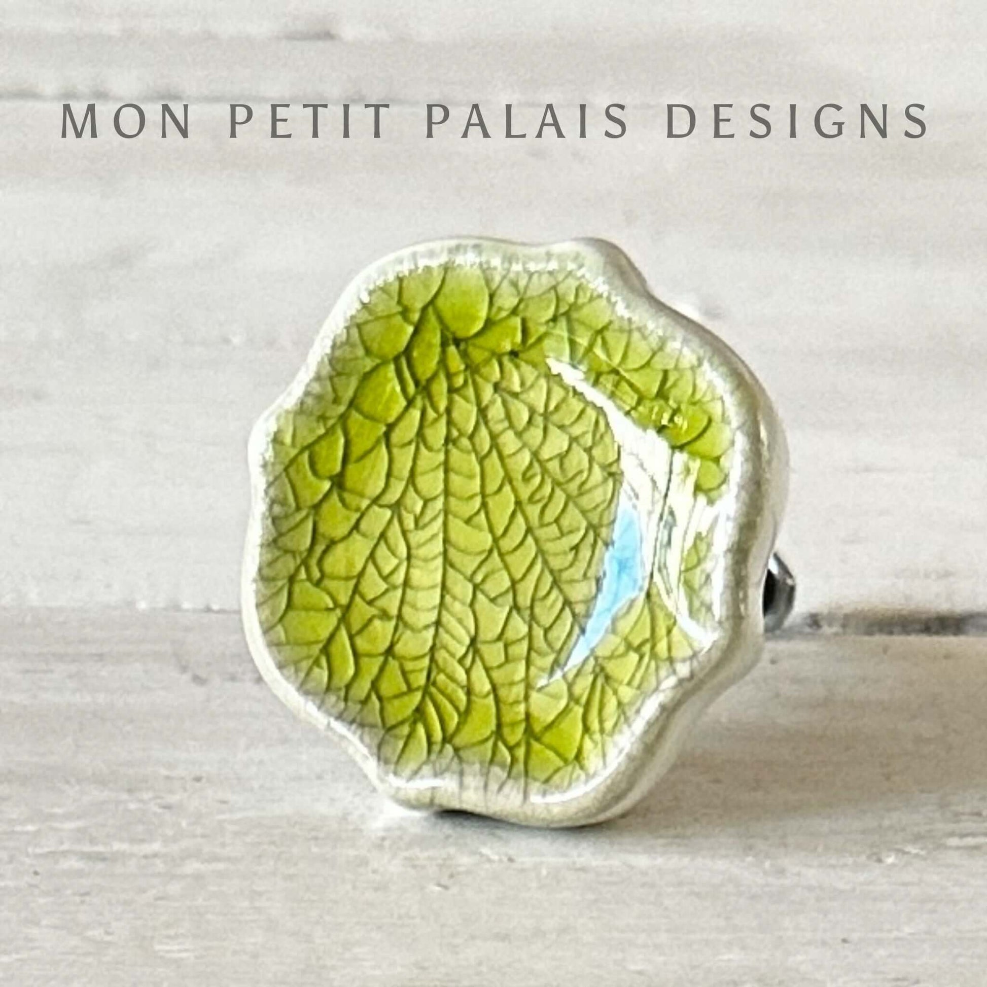 A zesty green crackle glass door knob with a textured surface, displayed against a light background with the text 'MON PETIT PALAIS DESIGNS'.