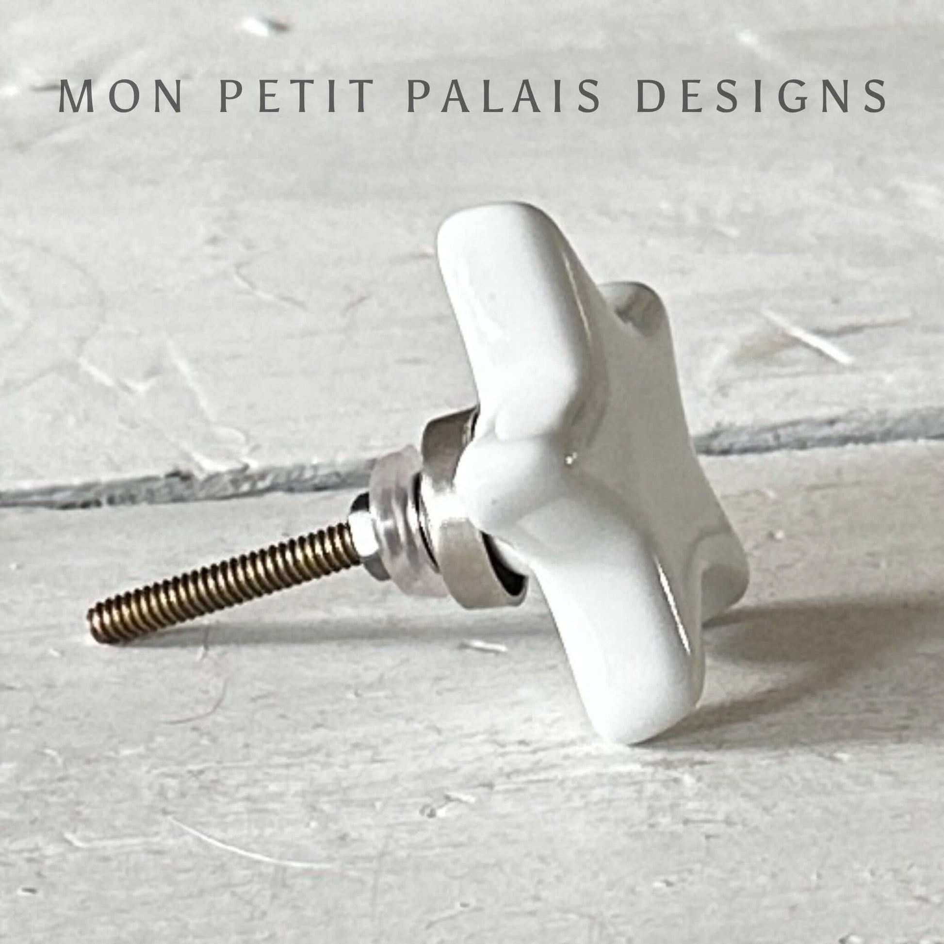 Side view of a white ceramic star knob with metal accents for furniture.