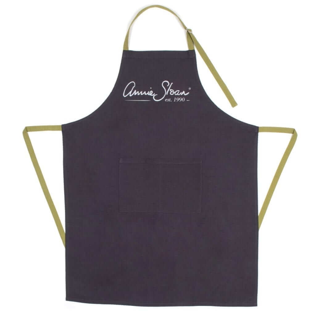 Black apron with gold straps and 'Annie Sloan' branding on a white background