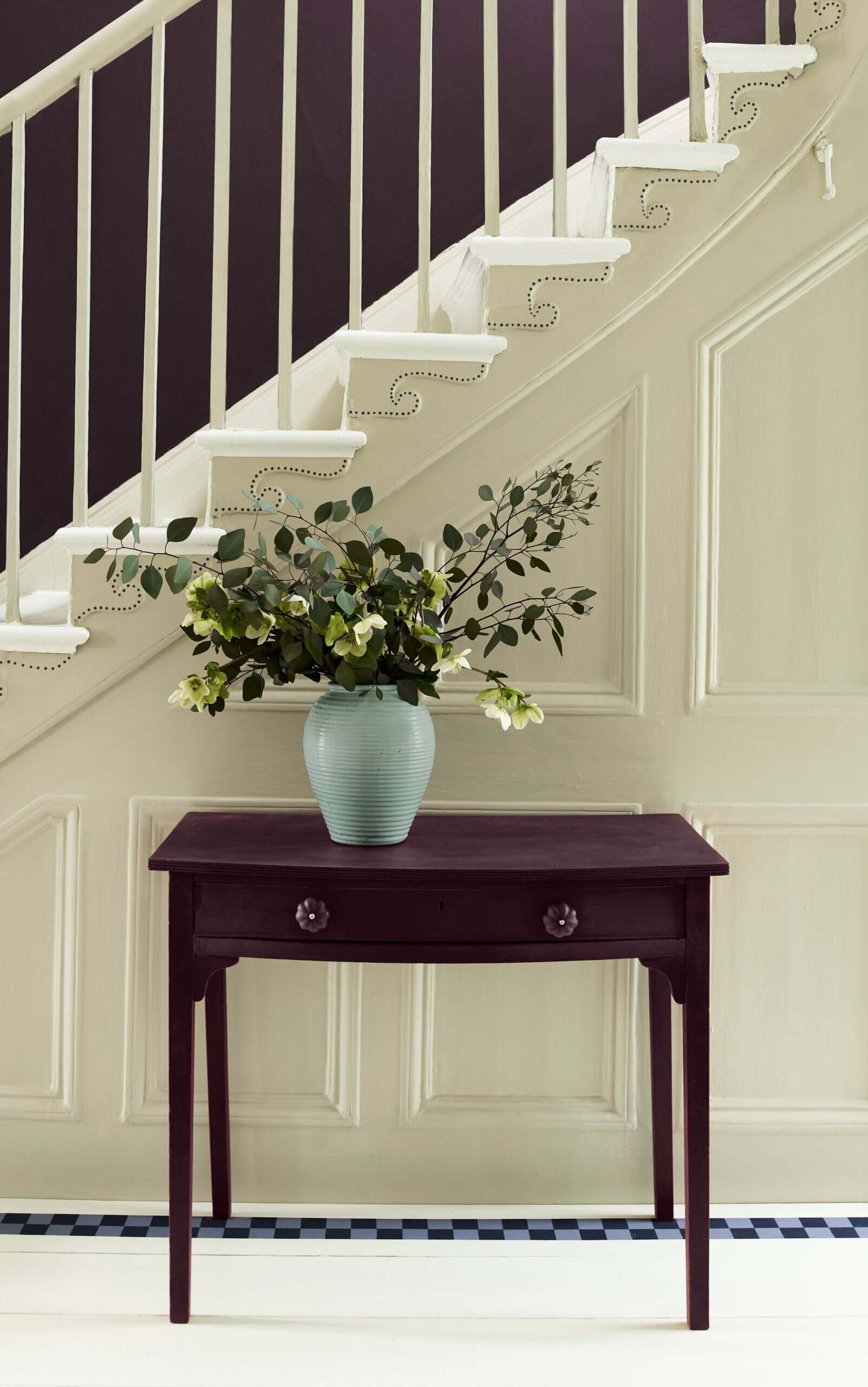 Elegant table with Tyrian Plum finish, adorned with a vase of greenery in a stylized home interior.