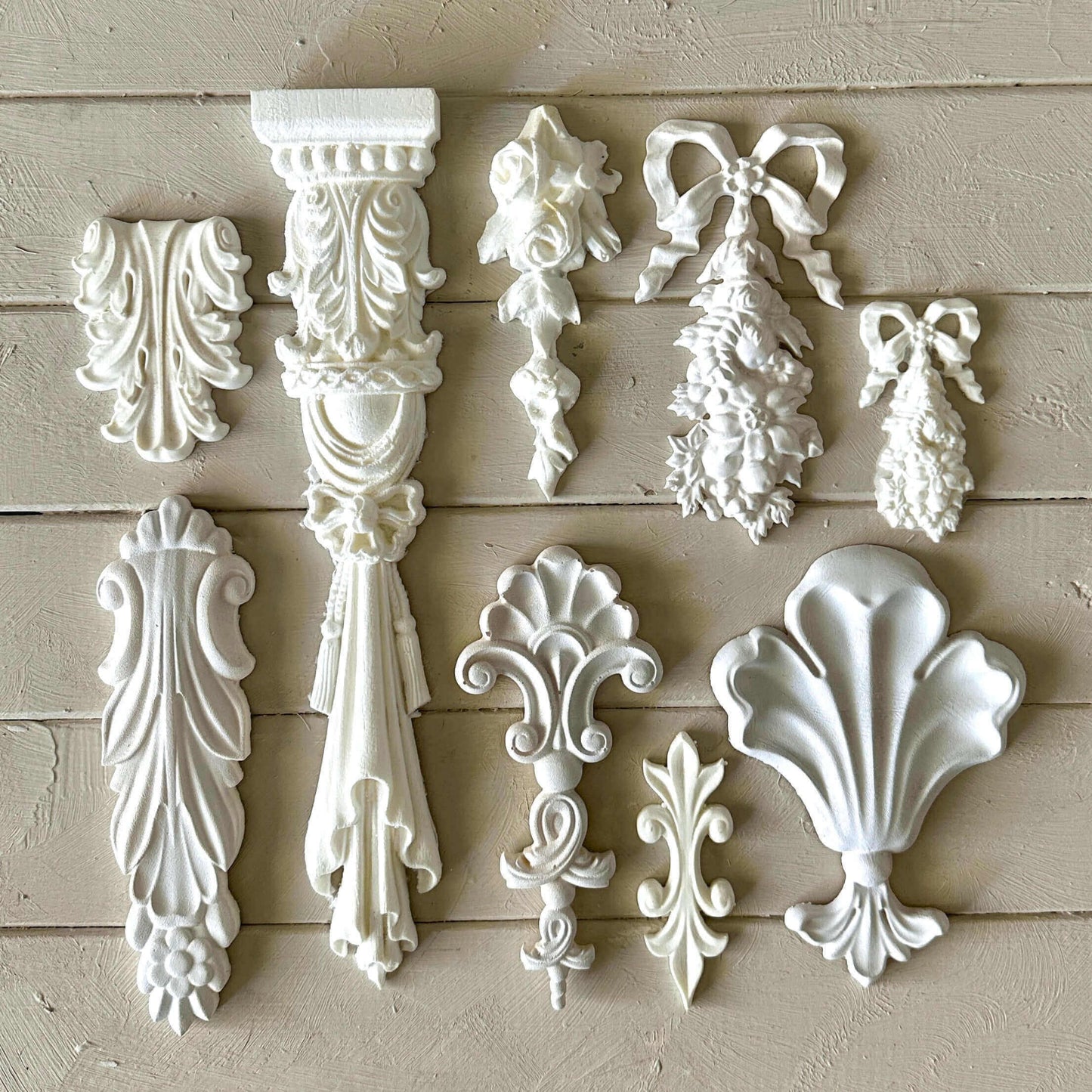 Collection of decorative white wall appliqués on a beige wooden background