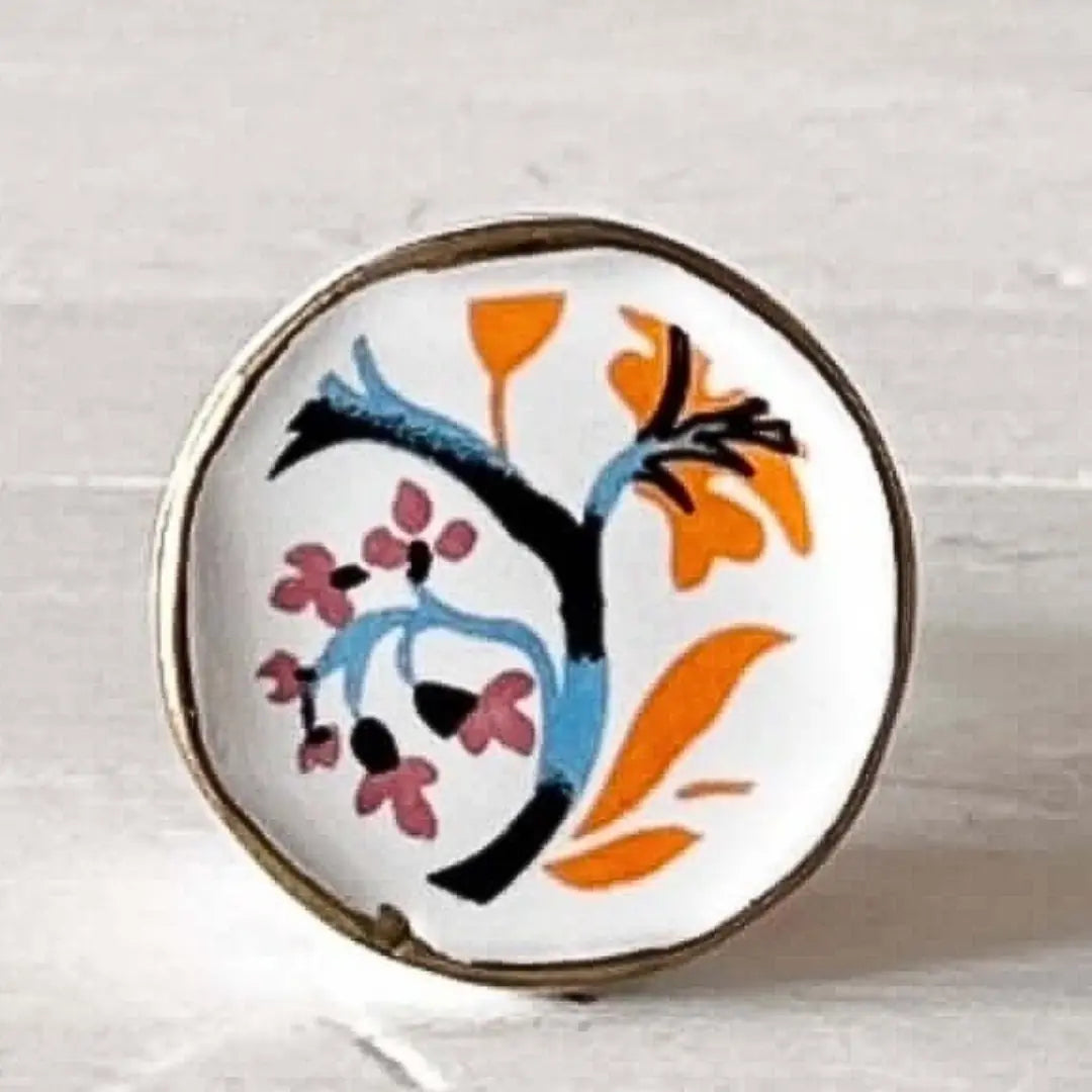 Orange & Blue Floral Hand-Painted Ceramic Knob with a bold boho floral design in blue, orange, and pink on a white ceramic base with gold trim.
