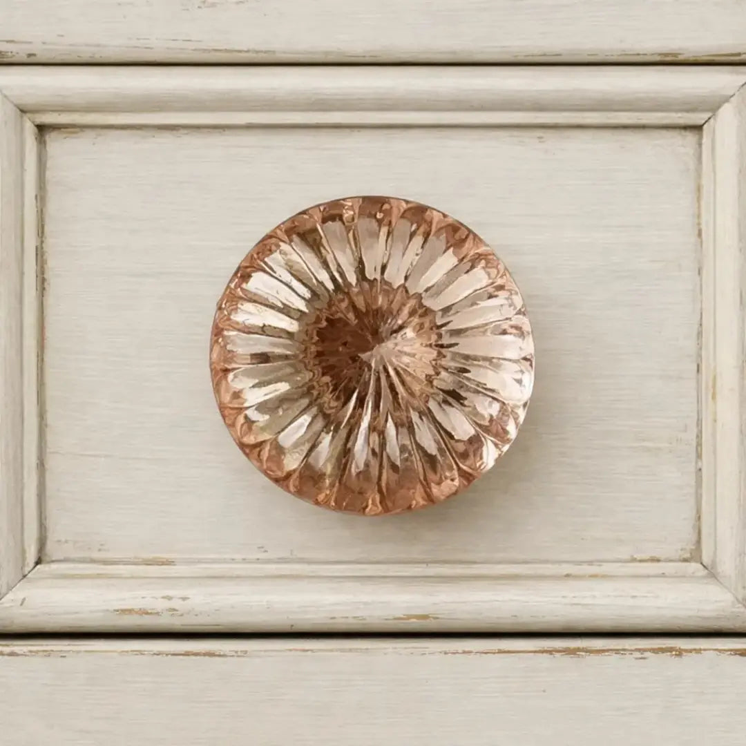 Rose quartz pink glass knob styled on a white worn painted drawer. 