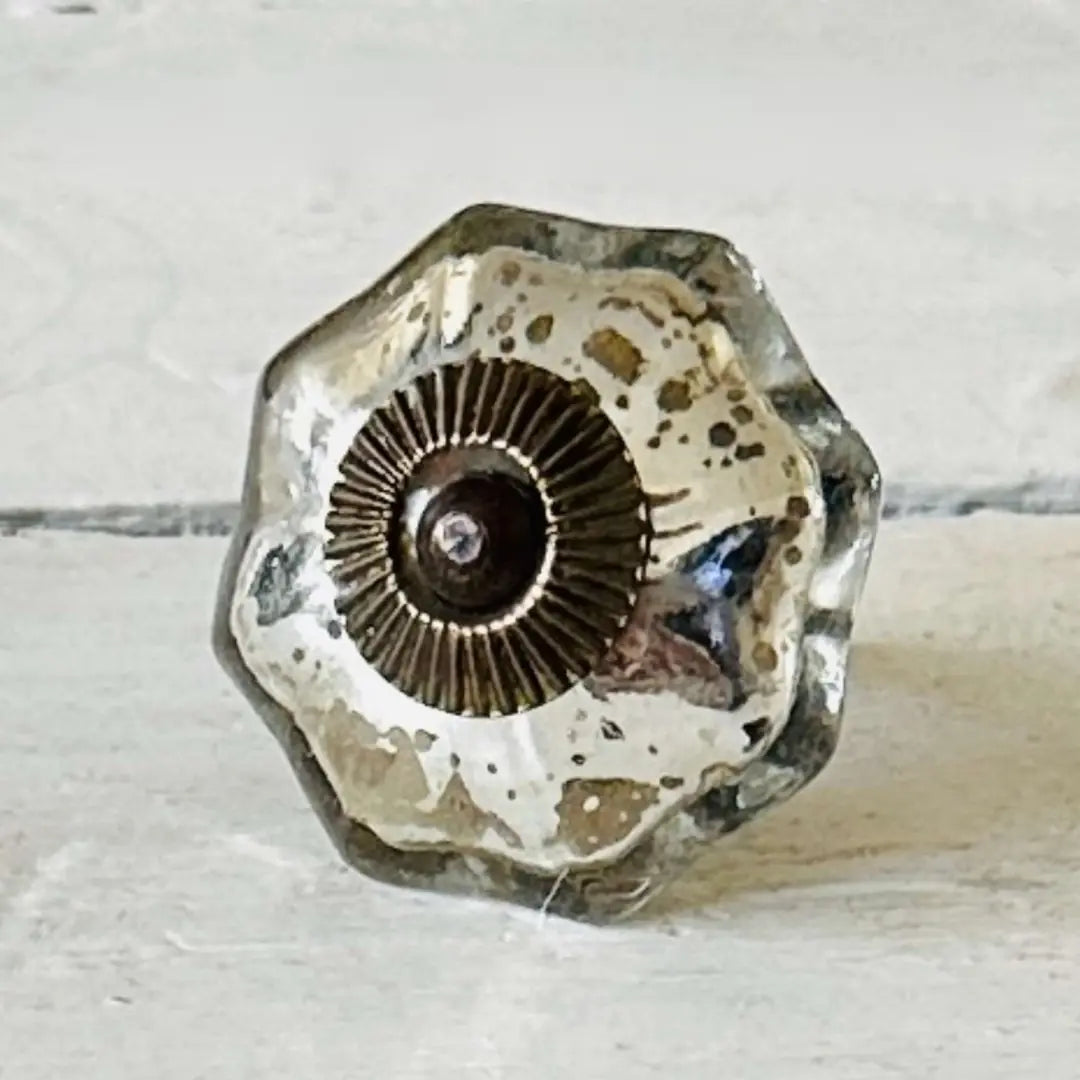 A close-up of the Vivienne mercury glass cabinet knob featuring a scalloped flower shape, silver-gold speckled finish, and a decorative metallic center.