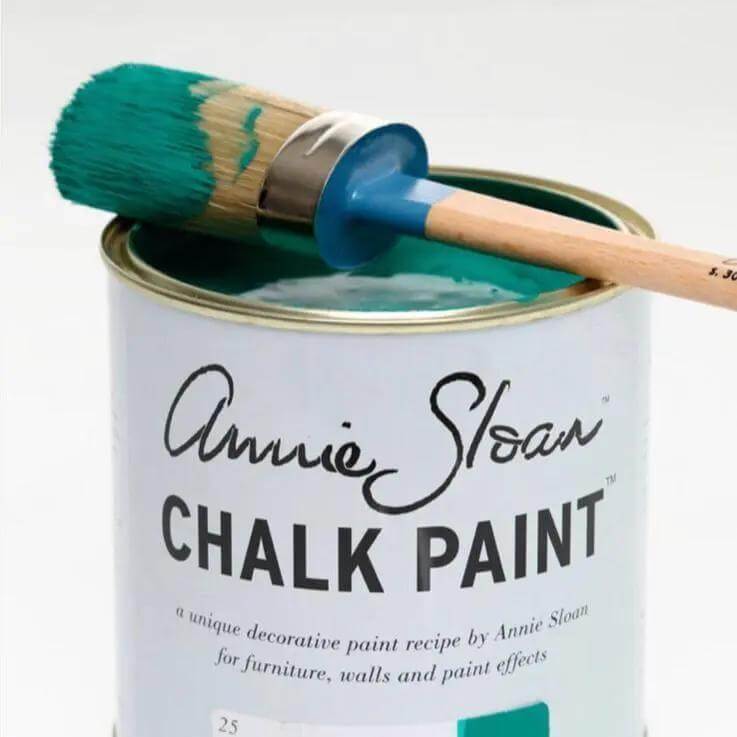 Annie Sloan Large Natural Bristle Paint Brush resting on a can of Chalk Paint with teal paint on the bristles.