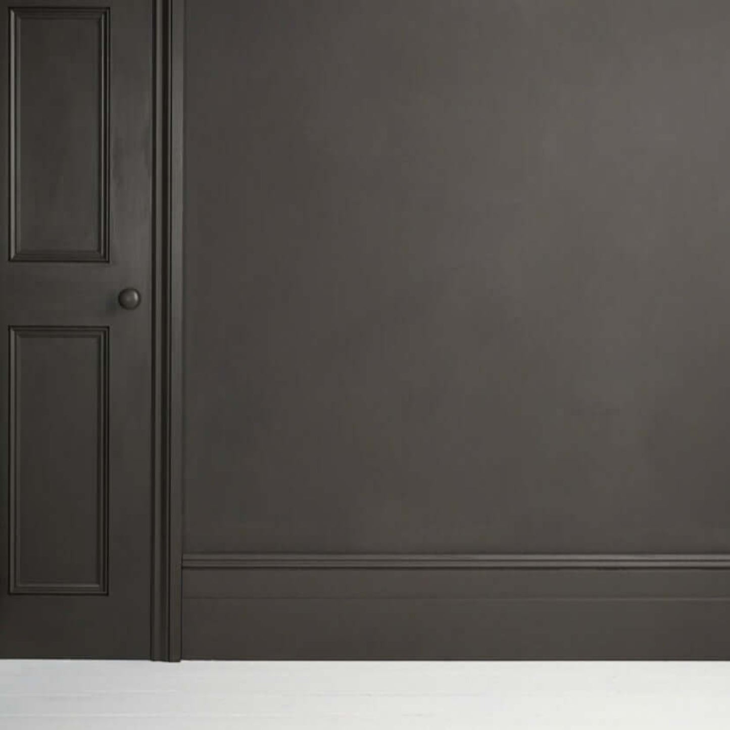 Graphite - Annie Sloan Satin Paint applied to a wall with a door, showcasing a dark grey chalkboard-like finish.