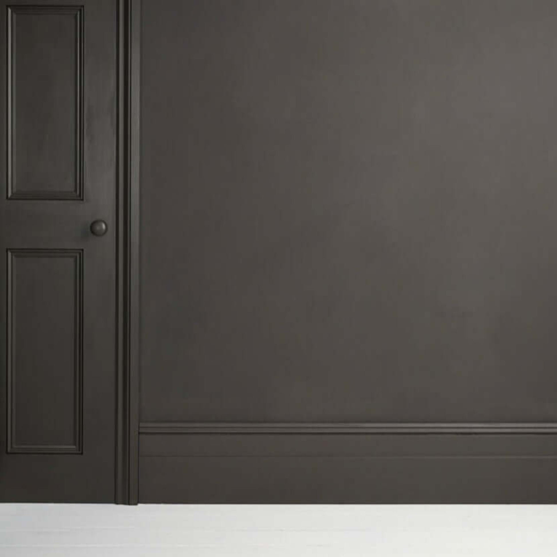 Graphite - Annie Sloan Satin Paint applied to a wall with a door, showcasing a dark grey chalkboard-like finish.