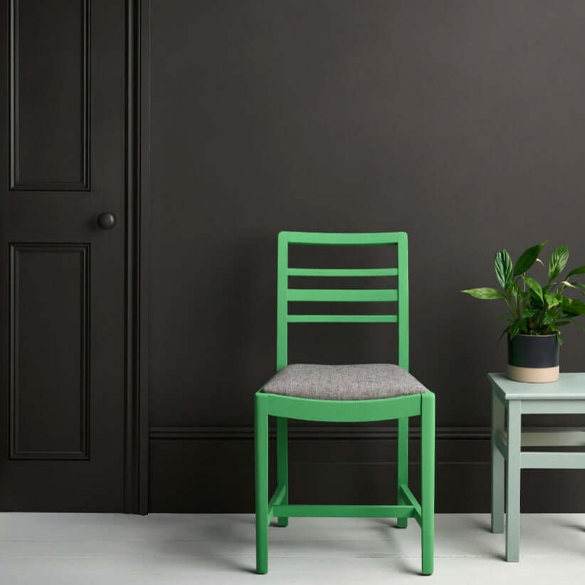 Graphite - Annie Sloan Satin Paint used on a dark wall with a green chair and plant.
