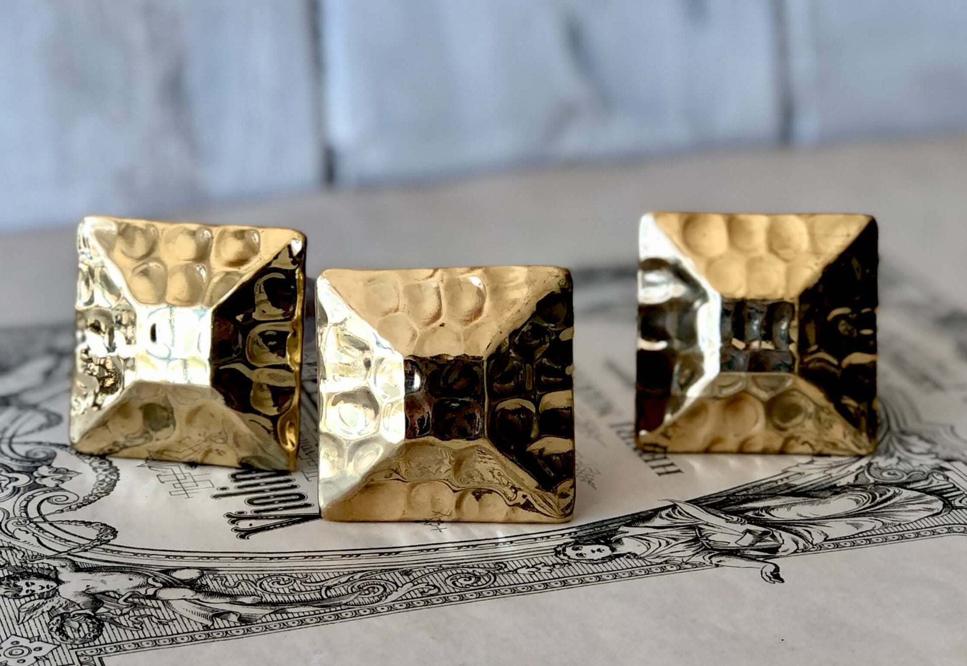 Close-up of hammered detail on square gold drawer knobs.