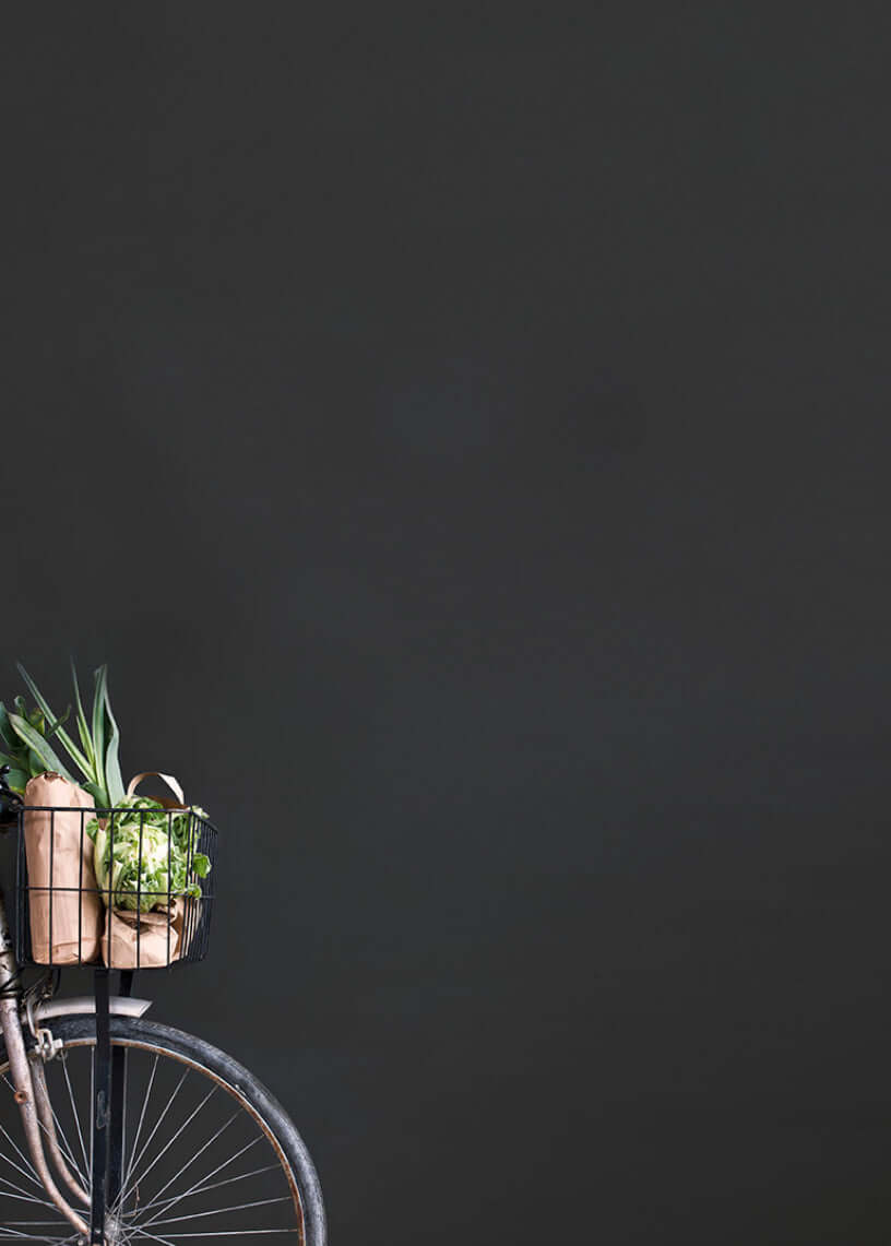 Vintage bicycle with a basket of fresh groceries against a dark background.